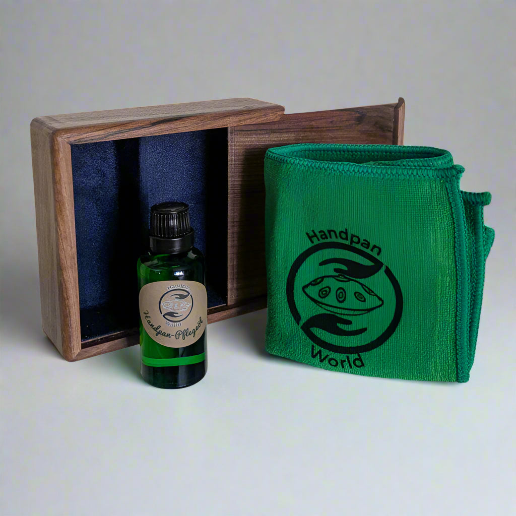 Handpan.World Pflege Kit für Handpans aus Edelstahl steht halb geöffnet auf einem Tisch. Ein Handpan Pflegeöl ist leicht zu sehen.