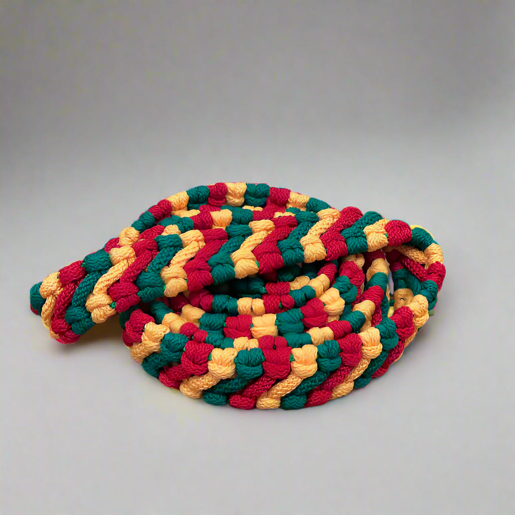 Handpan Schmuckband in den Farben Rot-Gelb-Grün liegt zusammengerollt auf einem Holzwagen