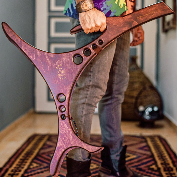 Ein kräftiger Mann hält eine Halterung für Handpans in der Hand, um seine Handpan auf ihr zu platzieren. Der Katanui Dekorations Ständer ist die perfekte Lösung zur ästhetischen Aufbewahrung für Dein Handpan Drum Instrument.