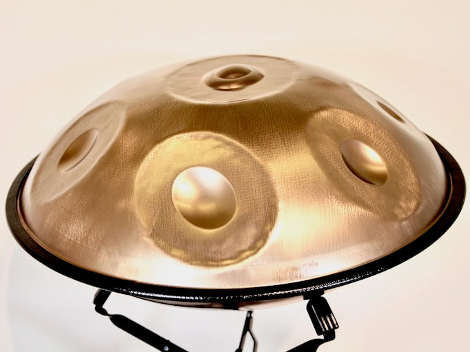 Eine Kupfer farbene Edelstahl Handpan Drum vom Hersteller Spirit Soul steht auf einem Handpan Ständer bereit gespielt zu werden.