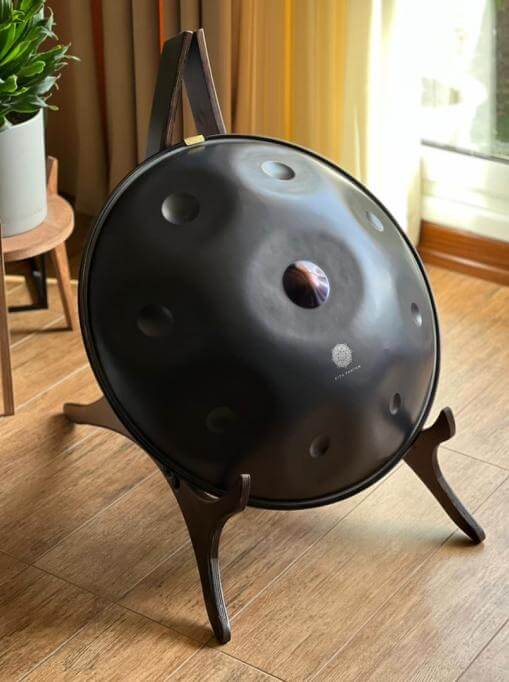 Eine Nitrierte Handpan ist einer hölzernen Halterung für Handpans in einem hellen Wohnzimmer aufgestellt. Der Katanui Dekorations Ständer ist die perfekte Lösung zum Aufbewahren für Dein Handpan Drum Instrument.