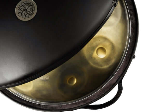 Leicht geöffnetes Handpan Hardcase im Black Classic Design, in dem eine Gold Vintage Kita Handpan liegt. Ein goldener Ausschnitt des Instruments ist zu sehen.  