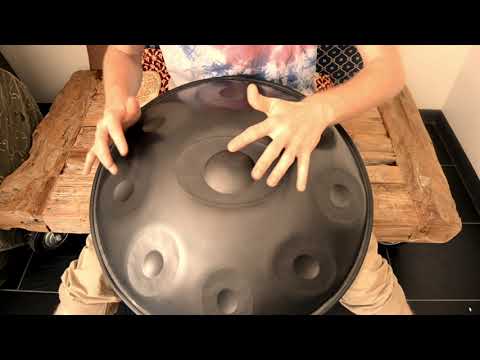 Handpanspieler sitzt auf einem Holzwagen und spielt auf einer Mystical D Kurd Handpan in nitriertem Stahl. Diese und Weitere Handpans gibt es online in unserem Store bei Handpan.World zu kaufen.
